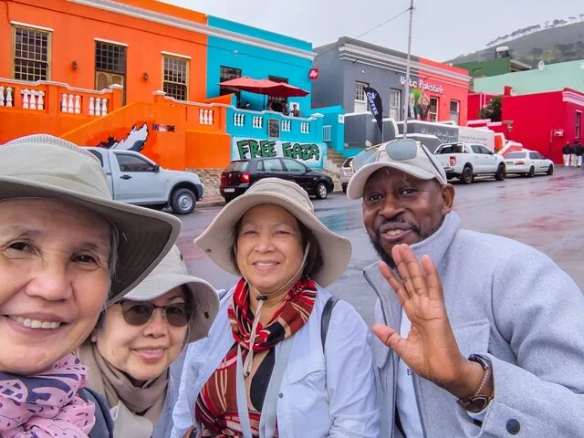 Eine Gruppe von Touristen macht ein Selfie vor den bunten Häusern von Bo-Kaap.